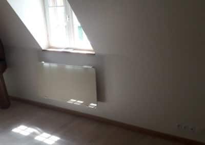 Radiateur électrique blanc sous une fenêtre dans des combles