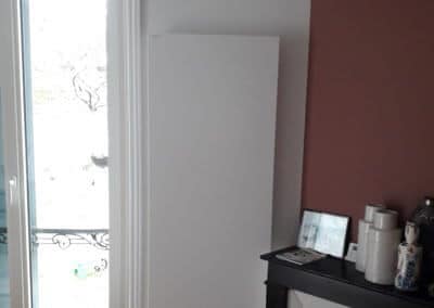 Grand radiateur en acier format vertical posé dans une chambre