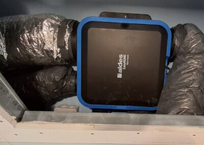 Caisson VMC hygroréglable Aldes EasyHOME extra-plat intégré en faux plafond avec raccordement des gaines de ventilation.