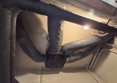 Caisson VMC hygroréglable Atlantic Hygrocosy fixé au plafond en pièce technique avec raccordement des gaines de ventilation.