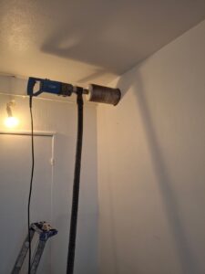 Carottage à sec Ø125 dans un mur en béton pour passage d’une gaine de ventilation de cuisine, avec récupération des poussières par aspirateur.