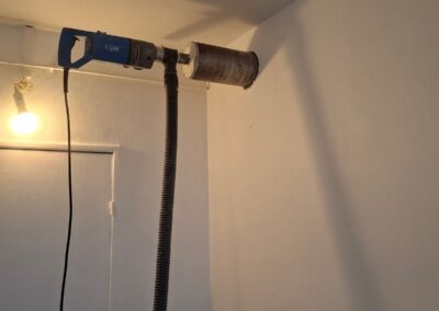 Carottage à sec Ø125 dans un mur en béton pour passage d’une gaine de ventilation de cuisine, avec récupération des poussières par aspirateur.