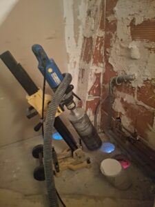 Carottage à sec de plancher en béton avec carotteuse sur support pour passage de gaines de ventilation VMC.