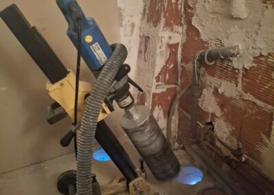 Carottage à sec de plancher en béton avec carotteuse sur support pour passage de gaines de ventilation VMC.