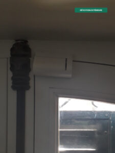 Contact d'ouverture sans fil Risco installé en partie haute d'une porte, détection d'intrusion par ouverture