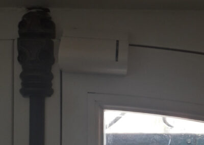 Contact d'ouverture sans fil Risco installé en partie haute d'une porte, détection d'intrusion par ouverture