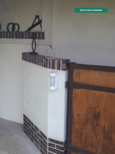 Détecteur d'approche extérieur Optex installé sur muret en bordure de jardin, étanche et immunisé animaux