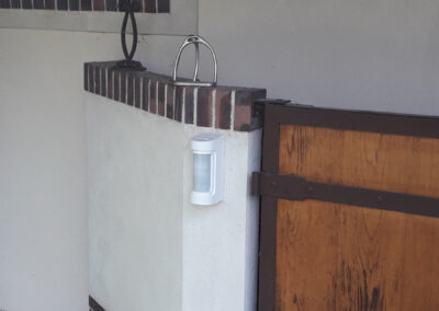 Détecteur d'approche extérieur Optex installé sur muret en bordure de jardin, étanche et immunisé animaux