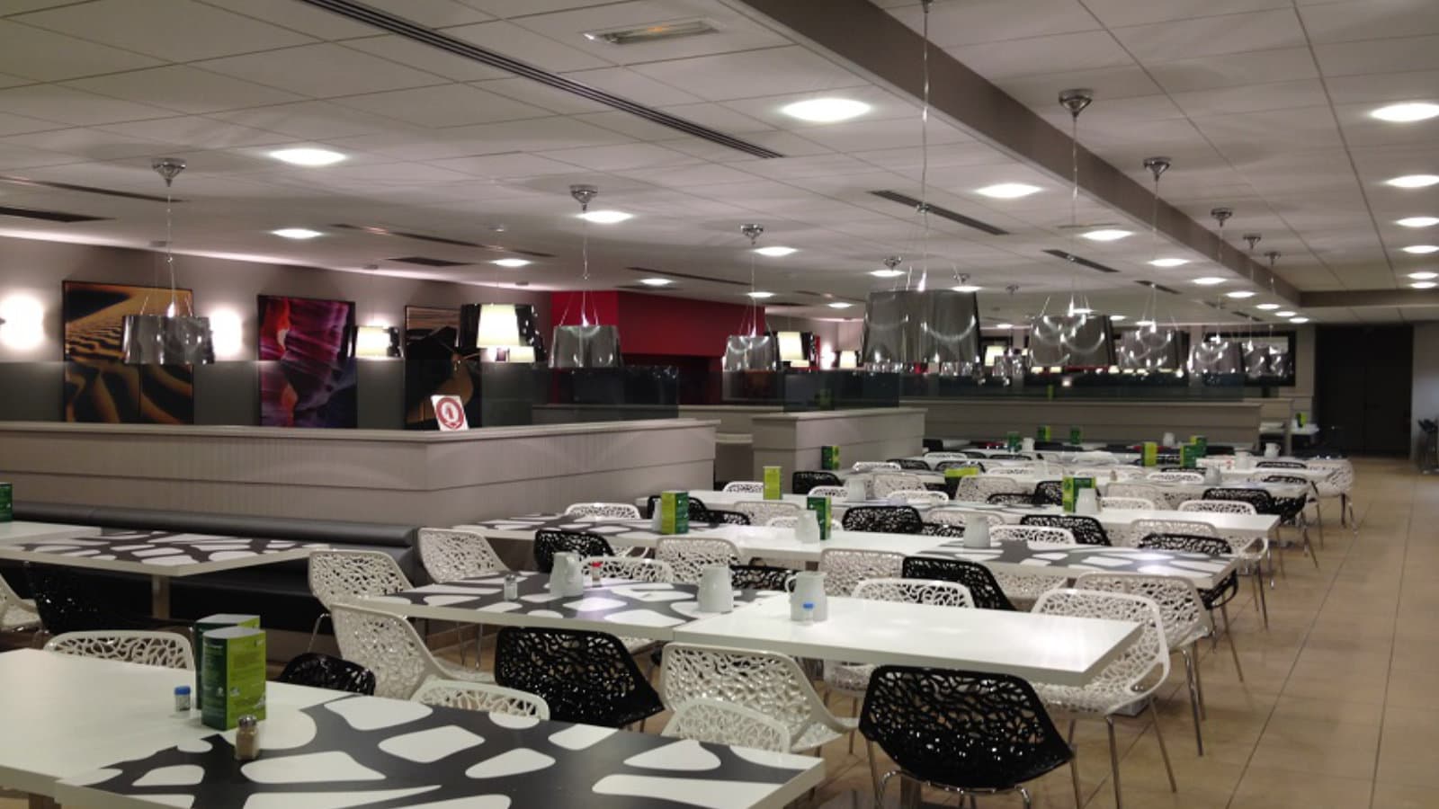 Eclairage LED d un restaurant interentreprises avec suspensions et downlights Éclairage LED dans un restaurant interentreprises avec suspensions au-dessus des tables et downlights LED encastrés